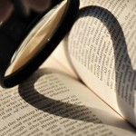 A magnifying glass creates a heart-shaped shadow on a book