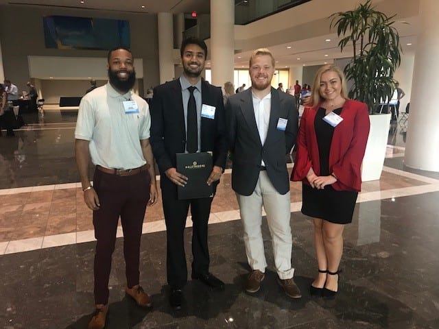 (Left to right) Malik Willis, Parth Patel, Benjamin Davidson and Deanna Long pose in front of the job fair area of the Fintech University Summit at the American Cancer Society building on Williams Street downtown on Oct. 10.