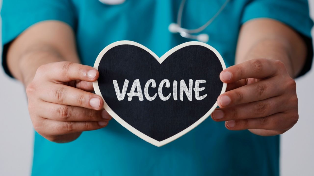Hands holding a heart image that reads "vaccine"