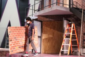 OU Student Donovan Lewis carries set pieces on stage for "Heathers: The Musical"