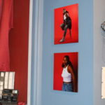 Photos of a young black woman on a red background are hung on a wall