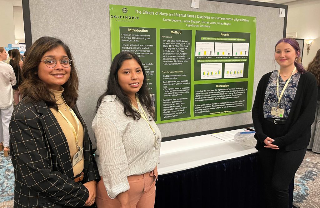 Three student with their poster explaining psychology research on "The Effects of Race and Mental Illness Diagnosis on Homelessness"