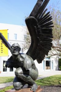 A state of a winged man crouches in front of the Conant Performing Arts Center