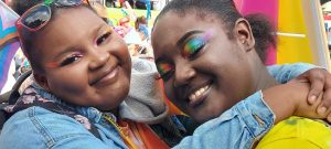 Two students hug and smile at the 2022 Atlanta Pride Parade