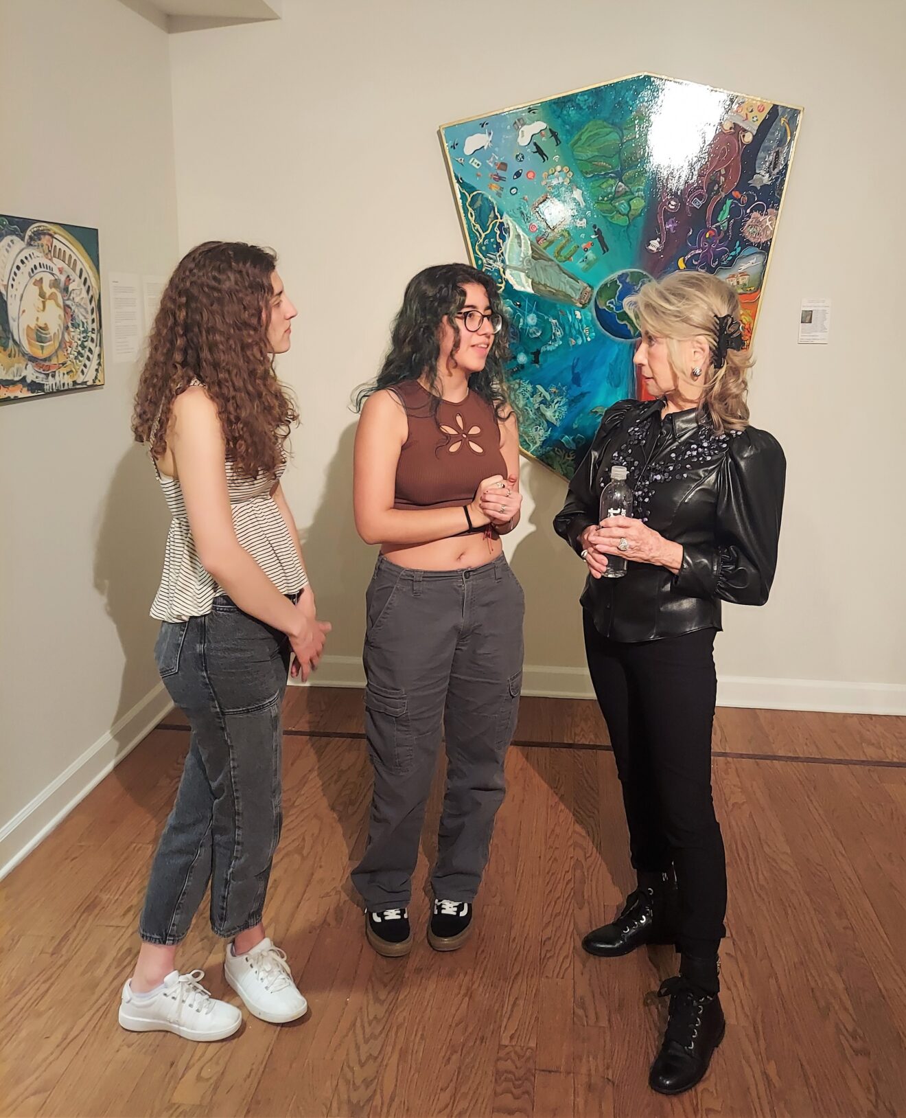 Artist and advocate Ruth Westreich speaks with two biology students during the opening reception for "Creating Conscious Conversations of Consequence" exhibition.