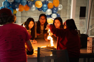 Students and visitors observing a bright flame from a "fire tornado" experiment.