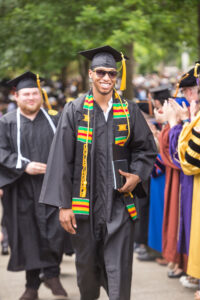 Black male graduate wearing cap and gown with his Kente stole.